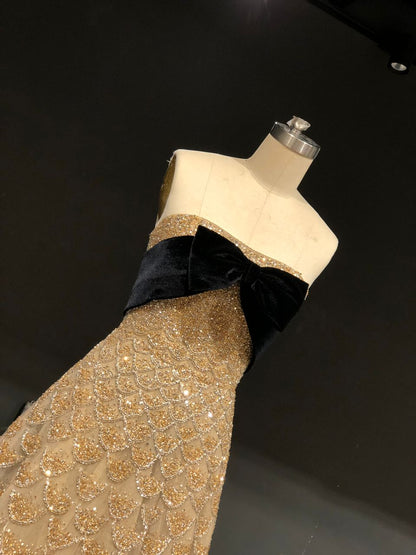 Strapless gold gown with crystal scales and a velvet bow